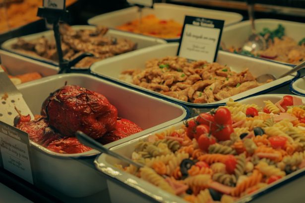 Buffet com saladas, carnes e pimentões recheados dispostos em travessas.